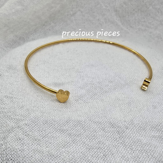 Gold bracelet on a textured white fabric background with 'precious pieces' text.